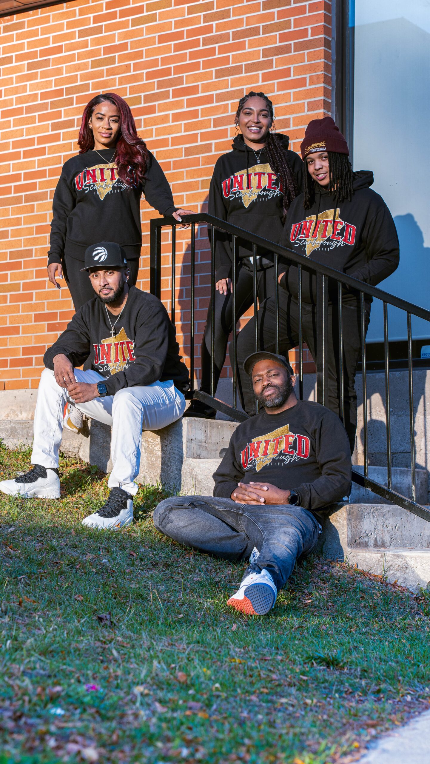 The USI leadership team wearing United Scarborough sweaters on brick steps
